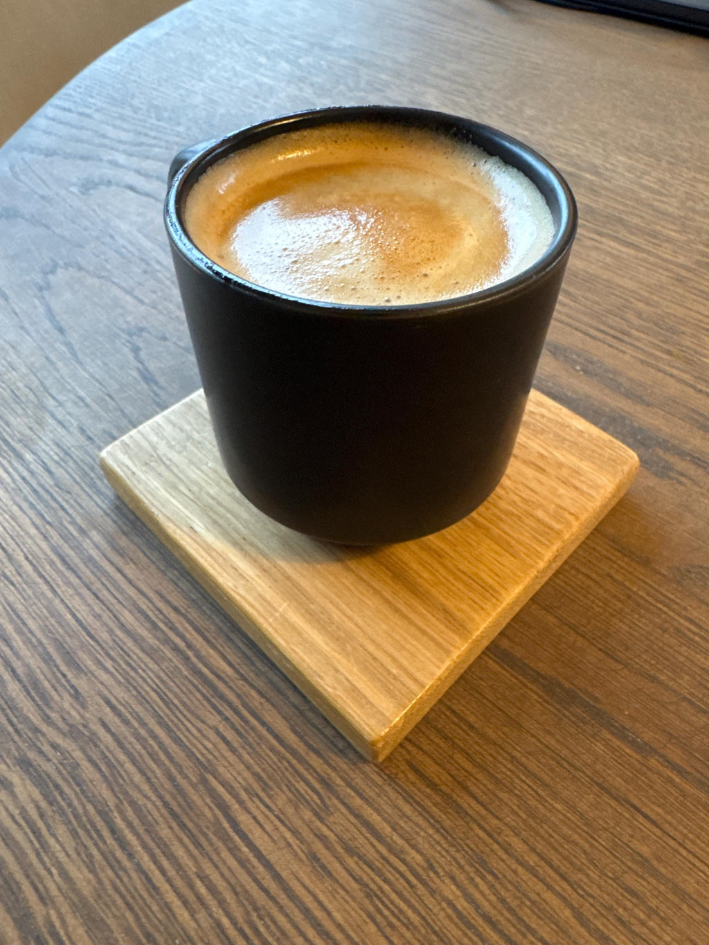 Tasse de café posée sur un dessous de verre en chêne massif