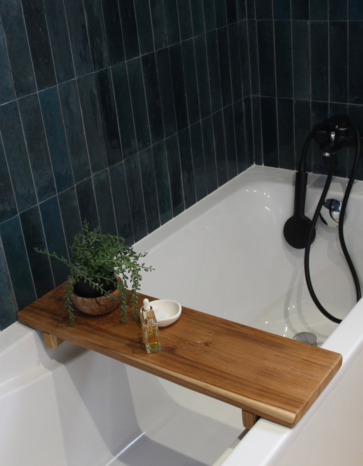 Plateau de bain en teck massif posé sur une baignoire, avec plante et bougie